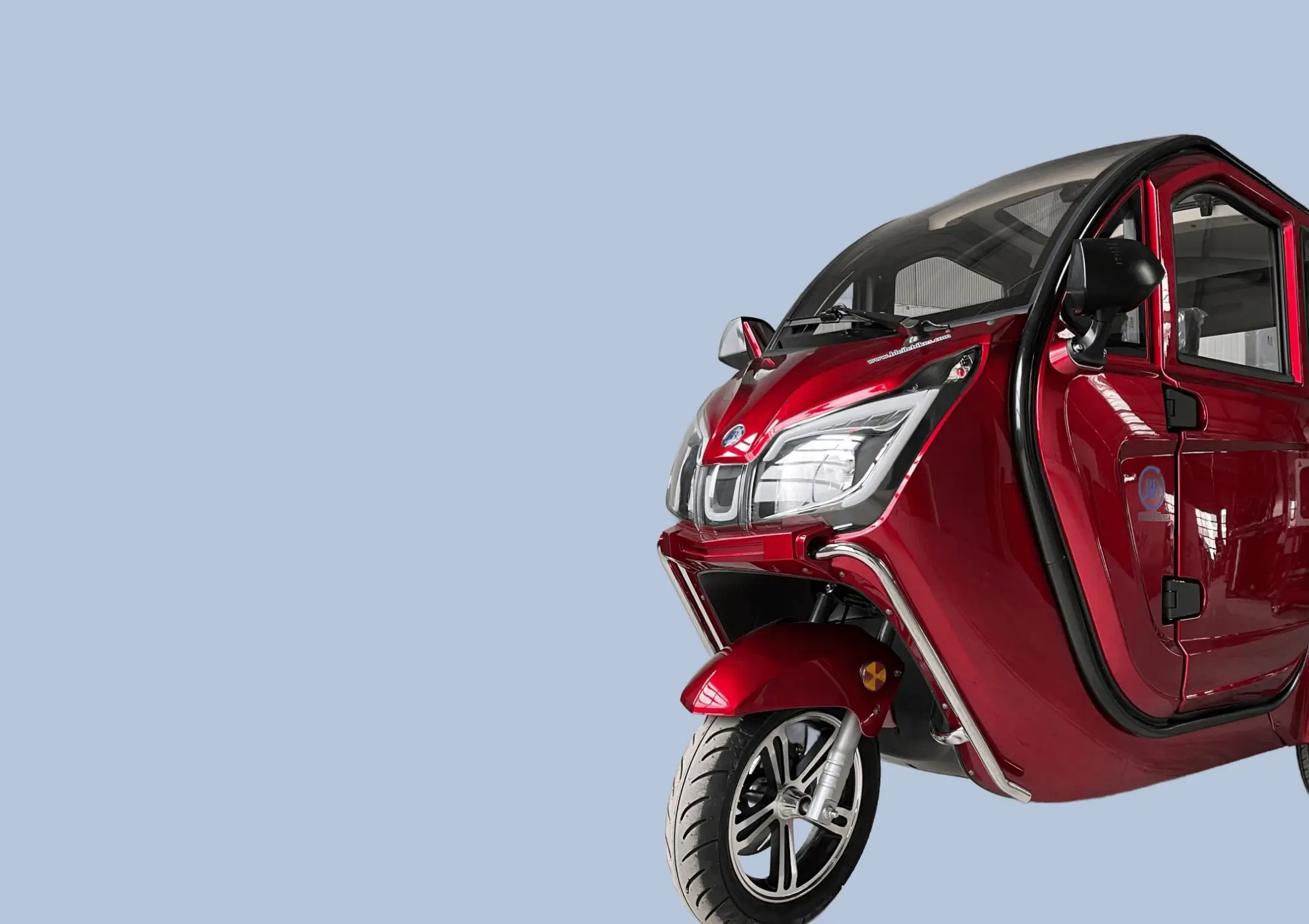 A red three-wheeled vehicle with a closed cabin is partially visible on the right. Text on the left reads “Bleile Bikes W3.” The background is light blue.